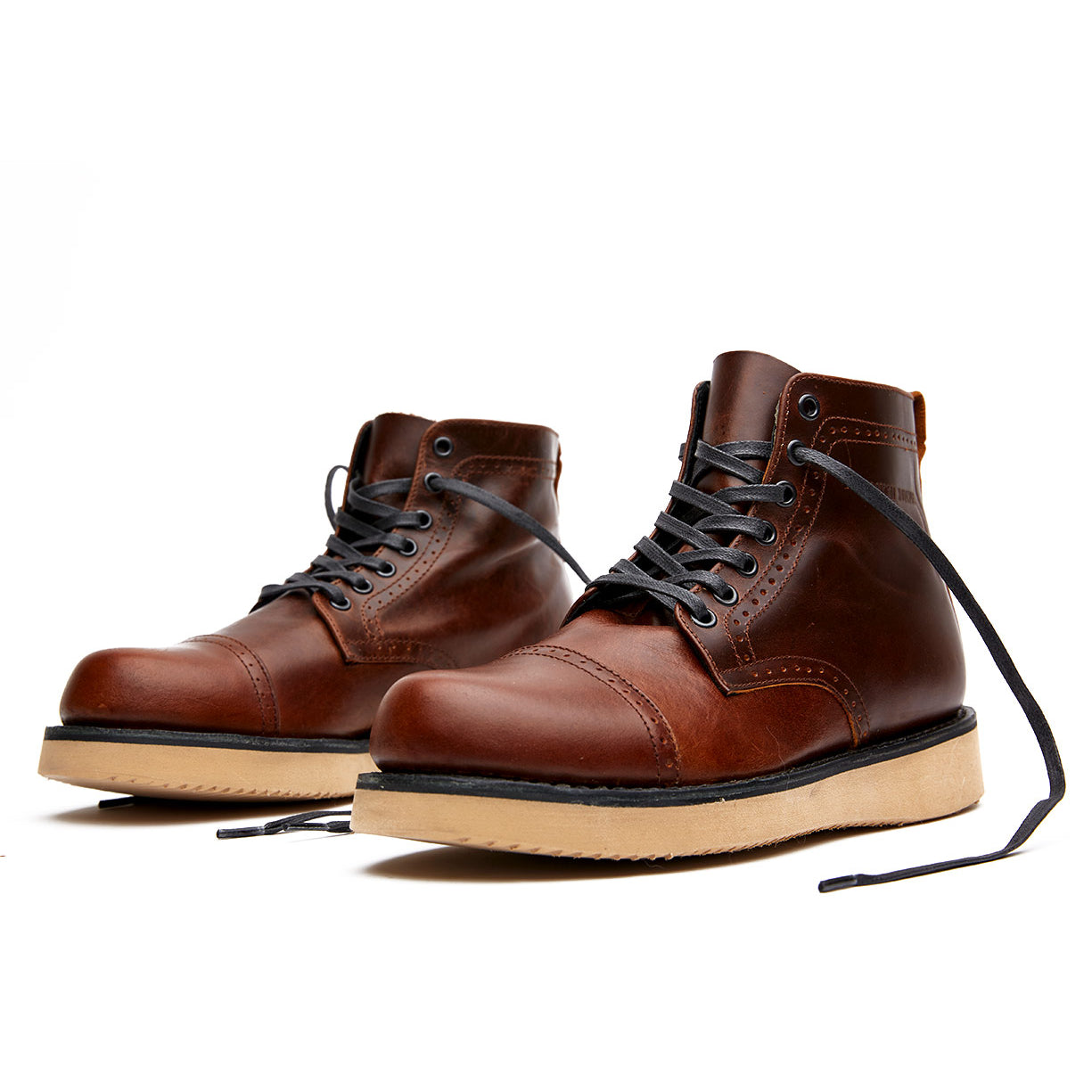 A pair of brown leather Broken Homme Shaun boots on a white background with a goodyear welt.