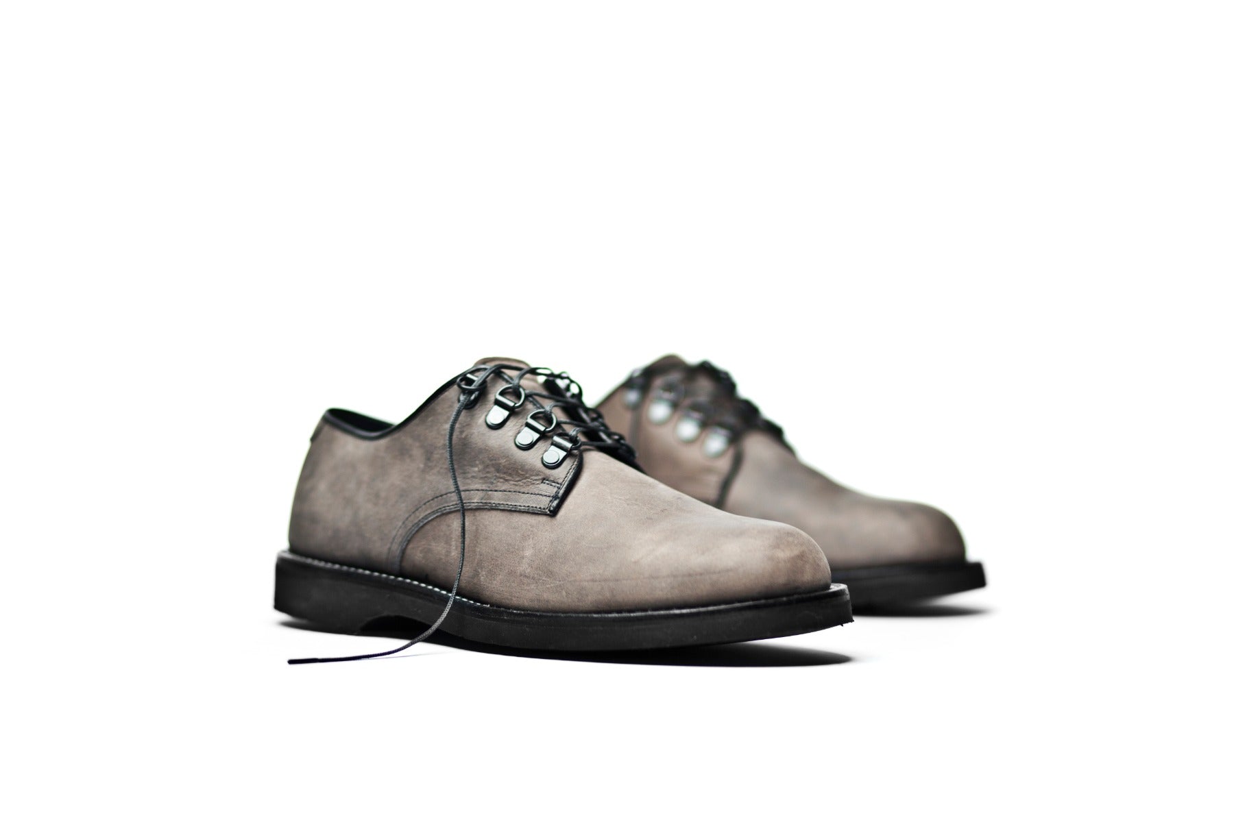 A pair of gray suede Oxford-style lace-up Billy shoes with black soles on a white background by Broken Homme.