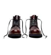 A pair of Aaron boots from the Broken Homme capsule collection, featuring a cap toe silhouette, displayed on a white background.