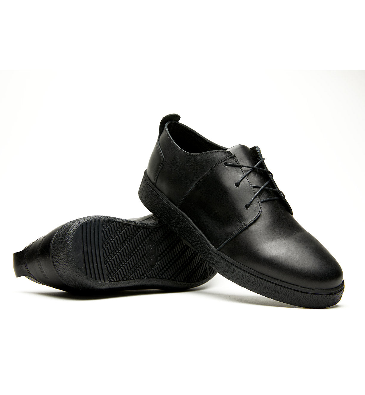 A pair of Broken Homme Ben Low black leather sneakers with a cork filled midsole on a white background.