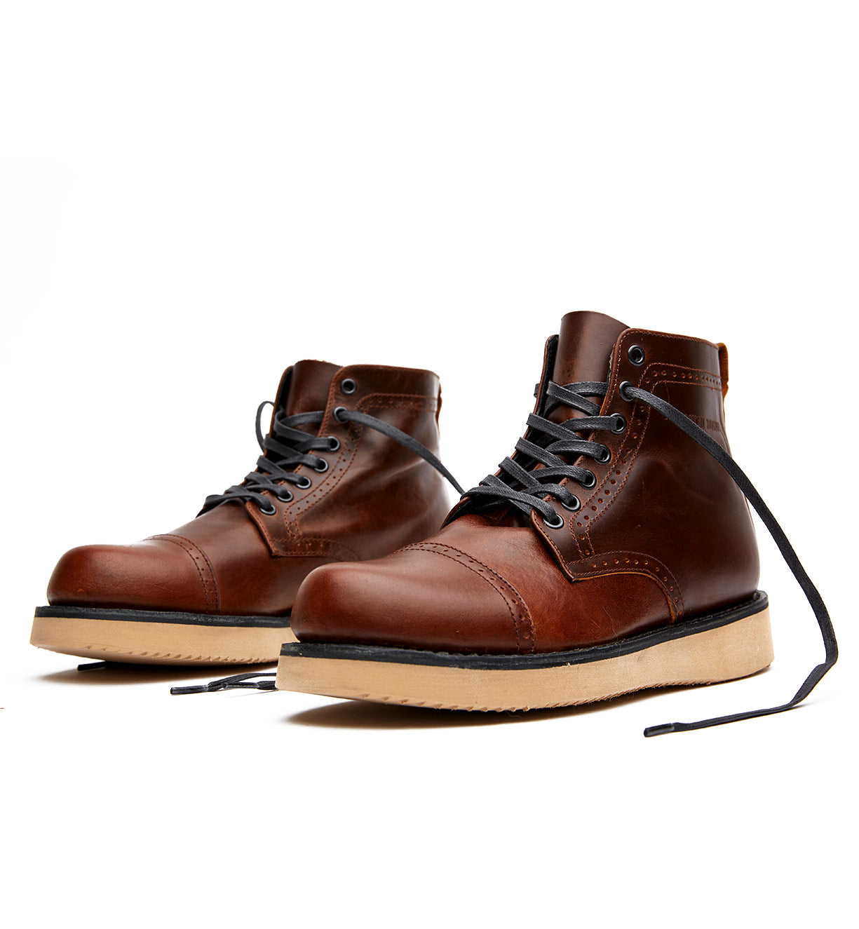 A pair of brown leather Broken Homme Shaun boots on a white background with a goodyear welt.