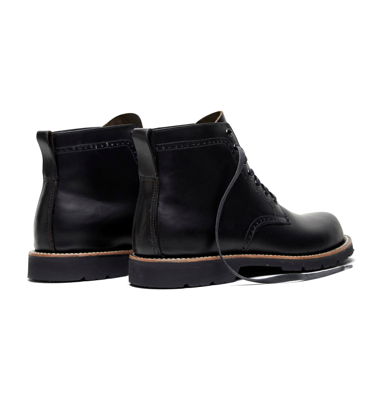 A pair of Tydus black boots with a refined style on a white background by Broken Homme.